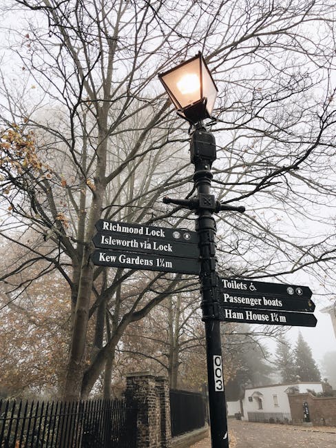 A black metal street lamp with a traditional lantern-style light fixture at the top, mounted on a tall pole, is prominently positioned in the foreground of the image. Attached to the pole are three re